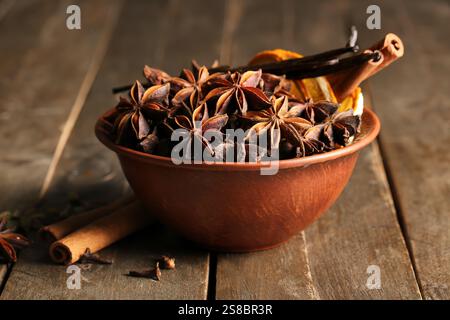 Schüssel mit Anissternen, Zimt und Vanillestangen auf hölzernem Hintergrund Stockfoto
