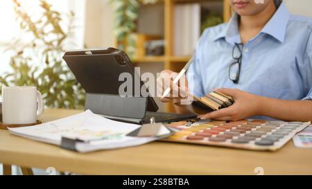 Innenarchitektin arbeitet am Schreibtisch und überprüft Farbmuster und Designmaterialien Stockfoto
