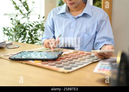 Innenarchitektin arbeitet am Schreibtisch und überprüft Farbmuster und Designmaterialien Stockfoto
