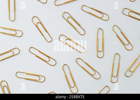 Goldene Büroklammern auf hellem Hintergrund, flach Stockfoto