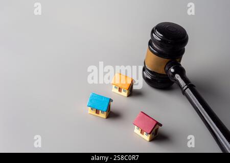 Ein Hammer und bunte Miniaturhäuser. Immobilienauktion oder Zwangsvollstreckung, Konzept des Immobilienrechts. Stockfoto