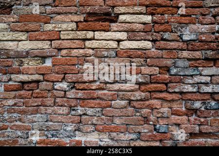 Eine detaillierte Ansicht einer rustikalen roten Ziegelwand mit strukturierten und verwitterten Oberflächen Stockfoto