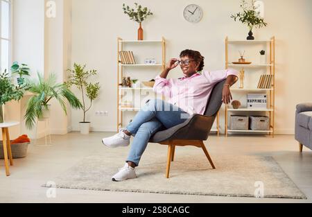 Porträt Einer Glücklichen Afroamerikanischen Frau, Die Zu Hause Im Sessel Lächelt Stockfoto