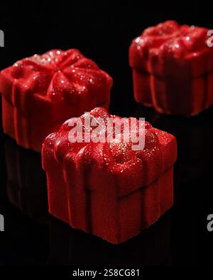 Kleine rote Mousse-Kuchen in Form einer Geschenkbox. Hausgemachte helle Mousse-Kuchen mit roter Velourbeschichtung. Stockfoto