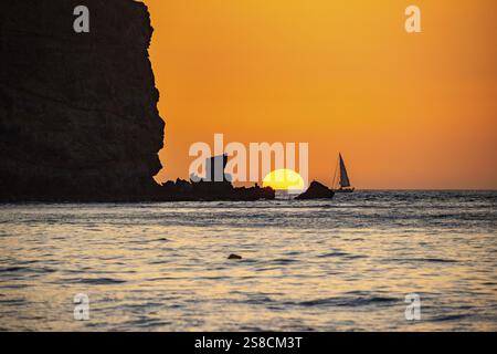 Sonnenaufgang während eines Sandsturms, Calima. Der schneebedeckte Horizont wird orange, wenn die Sonne wie ein Ball aufgeht. Ein Boot liegt im Meer vor Anker. Landschaftsfotogr Stockfoto