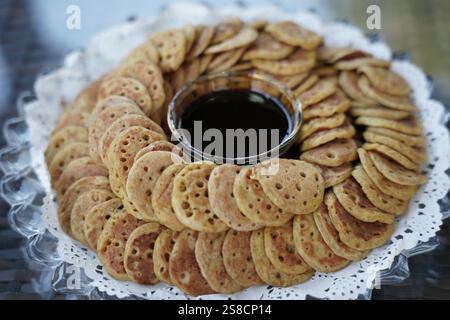 Eine wunderschön angeordnete Platte mit traditionellen Mini-Pfannkuchen serviert mit einer Schüssel mit reichem Dattelsirup. Perfekt für die Präsentation kultureller Küche, festliche tr Stockfoto