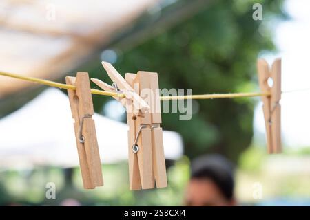 Ein buntes Haufen hölzerner Kleidernadeln hängt anmutig an einer straffen Wäscheleine und verleiht der Outdoor-Szene Charakter Stockfoto