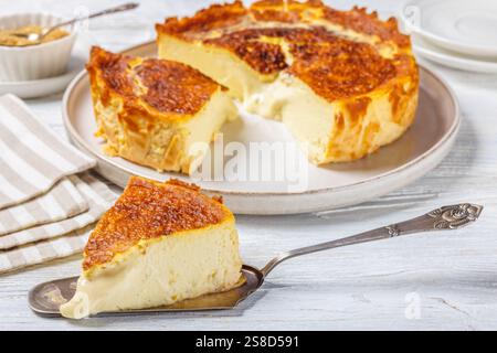 San Sebastian oder Basque verbrannte Käsekuchen Scheiben auf Teller und Kuchenschaufel auf weißem Holztisch, horizontale Ansicht von oben, Nahaufnahme Stockfoto