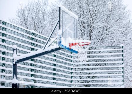 Schneebedeckter Basketballkorb auf einem Spielplatz im Freien im Winter. Stockfoto