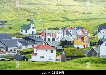Ein landschaftlich reizvolles skandinavisches Dorf, eingebettet in die Berge der Färöer, mit farbenfrohen Häusern und üppigen grünen Landschaften Stockfoto