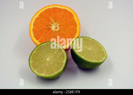 Gesunde und gesunde Lebensmittel, frisches Obst. Schöne Scheiben, Hälften von Orange, grüne Limette sind auf einem weißen Kunststoffhintergrund angeordnet. Stockfoto