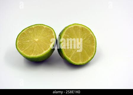 Gesunde und gesunde Lebensmittel, frisches Obst. Schöne Scheiben, Hälften grüner Limette befinden sich auf einem weißen Kunststoffhintergrund. Stockfoto