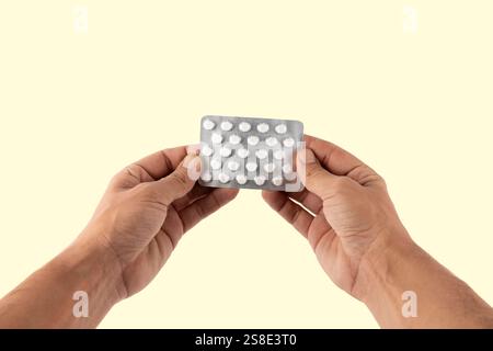 Männliche Hände, die eine Arzneimittelblase auf gelbem Hintergrund halten Stockfoto