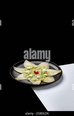 Ein Gourmet-Dessert mit frischen Kiwi- und Birnenscheiben, die elegant auf einem schwarzen Teller angeordnet sind. Die minimalistische Präsentation hebt die natürlichen Farben hervor Stockfoto