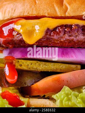 Ein Käseeburger mit Rindfleisch, geschmolzenem Käse, Gurken, Tomaten, Salat, rote Zwiebeln und Ketchup schaffen ein köstliches, mehrschichtiges Sandwic Stockfoto