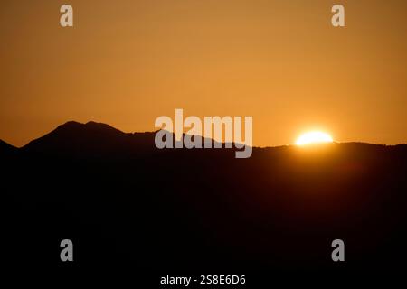 Ein atemberaubender Blick auf den Sonnenaufgang über der Silhouette der zerklüfteten Berge von Alicante, der die Szene in einem warmen goldenen Glanz taucht, der die Highlights hervorhebt Stockfoto