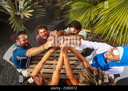 Eine multiethnische Gruppe von Freunden, die ein verspieltes Treffen im Freien genießen und an einem lustigen Ratespiel teilnehmen, teilen Lachen und Kameradschaft in einem vib Stockfoto