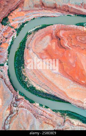 Dieses Bild fängt die atemberaubende Luftperspektive von Rio San Juan's Serpentinfluss ein, der durch leuchtende rote Felsformationen in Utah, USA, führt Stockfoto