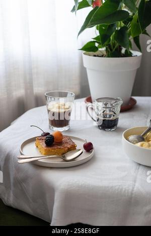 Der Couchtisch wird mit einem köstlichen Stück Kuchen mit frischen Beeren belegt, begleitet von einem Glas mehrschichtigen Kaffee und einer Schüssel Eis, Creati Stockfoto