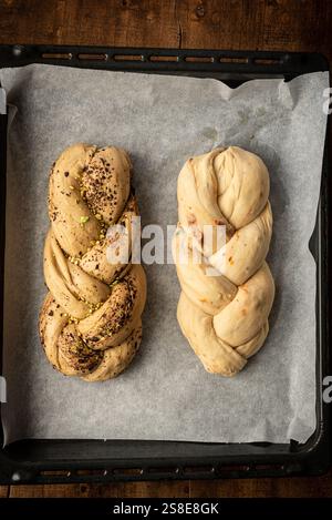 Blick von oben auf frisch gebackenes Bakbah-Brot auf Pergamentpapier, mit einem Laib mit Pistazien und Gewürzen, und dem anderen subtil mit ch angereichert Stockfoto