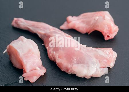 Ein Nahaufnahme-Foto mit frischen rohen Hasenfleischstücken auf einer dunklen Steinoberfläche, die Textur und Farbe hervorhebt, ideal für kulinarische Zwecke oder Stockfoto