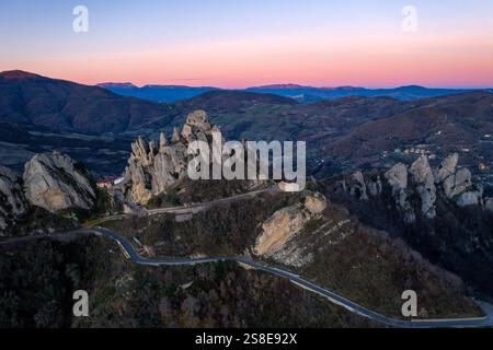 Ein atemberaubender Blick aus der Luft auf Pietrapertosa, hoch oben in den lukanischen Dolomiten bei Sonnenaufgang. Die felsigen Gipfel und gewundenen Straßen werden vom so beleuchtet Stockfoto
