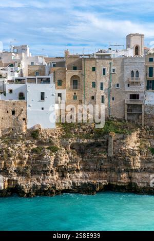 Wunderschöne Häuser aus Stein und weiß getünchten Steinen auf Klippen in Polignano a Mare, mit der Adria darunter und dem zeitlosen Charme von Apulien. Stockfoto