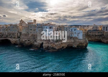 Herrlicher Blick auf die Stein- und weiß getünchten Gebäude von Polignano a Mare, die auf felsigen Klippen über der pulsierenden Adria unter dramatischen Wolken und thront Stockfoto