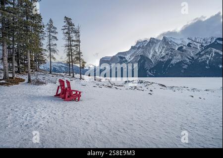 Rote Stühle am Ufer des gefrorenen Lake Minnewanka im Banff National Park, Alberta, Kanada Stockfoto