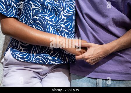 Nahaufnahme eines multiethnischen LGBTQ+-Paares, das sich umarmt und Hände hält und Liebe und Einheit symbolisiert. Die verschiedenen Kleidungsmuster spiegeln Individualität und Stile wider Stockfoto