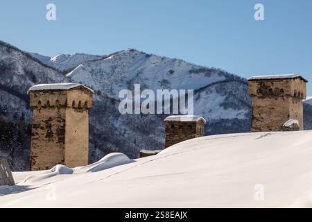 Majestätische Steintürme stehen inmitten einer riesigen, schneebedeckten Landschaft mit hoch aufragenden, zerklüfteten Bergen im Hintergrund in Georgien Stockfoto