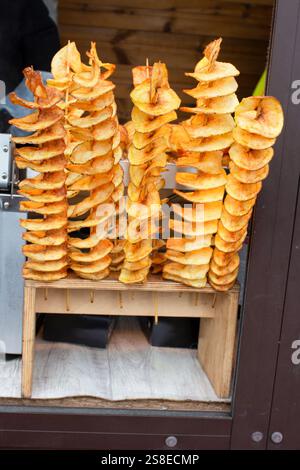 Kartoffelchips auf einem Spieß. Spiralkartoffeln gebraten, auf Holzstäbchen. Streetfood, eine spiralförmige gebratene Kartoffel auf einem Stock. Stockfoto