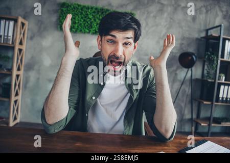Frustrierter junger Mann, der Wut am Arbeitsplatz in ungezwungener Büroumgebung ausdrückt Stockfoto