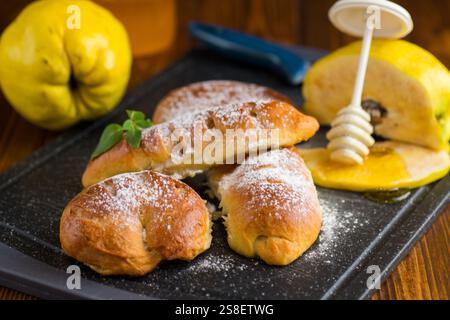 Gebäck. Süße Brötchen mit Quitte- und Honigfüllung auf einem Holztisch. Stockfoto