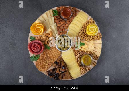 Jarcuterie umfasst verschiedene Würstchen, Käse, Nüsse, Cracker und Obst. Moderne Version von festlichen Snacks auf Holzbrett Stockfoto