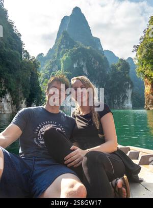 Ein Paar genießt am Nachmittag eine Bootsfahrt auf einem ruhigen See, umgeben von majestätischen Bergen Stockfoto