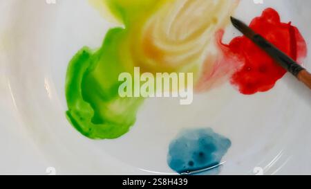 Aquarellpalette mit gelber, grüner und roter Farbe und einem Pinsel auf weiß. Stockfoto
