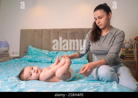 Ihr Baby greift den Finger fest, seine winzige Hand betont die starke Bindung zwischen Mutter und Kind, eingerahmt von der weichen Textur des leuchtenden Blaus Stockfoto