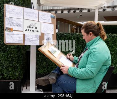Los Angeles, Kalifornien, USA. Januar 2025. Die Künstlerin ASHER BINGHAM arbeitet auf einem Foto von Google Street View und beginnt mit der Arbeit an einer Skizze eines Altadena-Hauses, das beim Eaton-Brand zerstört wurde. Obwohl sie in der Regel von zu Hause aus arbeitet, nimmt Frau Bingham heute an einer Veranstaltung „We Love LA“ in der Westfield Century City Mall Teil, die von FIGS, einer medizinischen Uniformen- und Bekleidungsfirma mit Sitz in Santa Monica, gesponsert wird. Ms. Bingham begann mit dem Zeichnen verbrannter Häuser mit einer Zeichnung eines Hauses, das von einem Freund verloren ging. Bald verbreitete sich die Nachricht, dass sie sich bemühte, Feueropfern eine Erinnerung zu geben, und sie hat jetzt eine stabile o Stockfoto