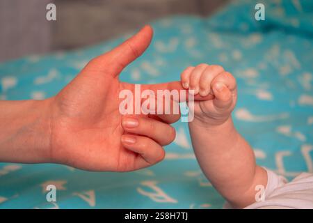 Eine Nahaufnahme fängt die winzige Hand eines Babys ein, das sich am Finger eines Elternteils festhält und Vertrauen und Liebe zum Ausdruck bringt. Stockfoto