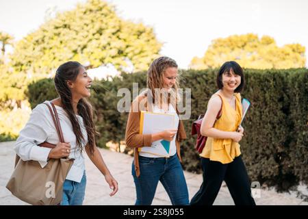 Glückliche Austauschstudenten, die auf dem Universitätscampus spazieren gehen und plaudern Stockfoto
