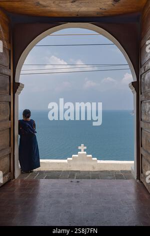 San Antonio Palopo, Solola, Guatemala. März 2024. Frau, die von der San Antonio Palopo Kirche über den Atitlan-See schaut. Stockfoto