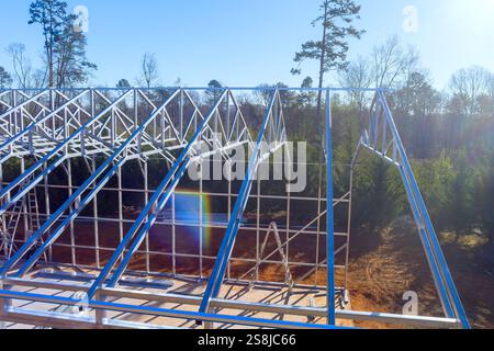 Die Arbeiter bauen stabile IT-Stahlträgerrahmen für neue Gebäude, die von einem Metalllager umgeben sind Stockfoto