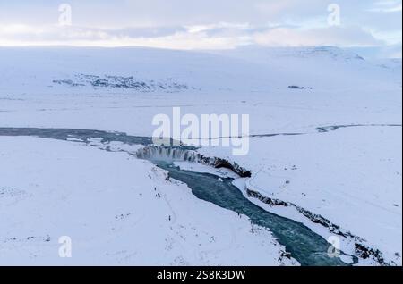 Panoramablick auf den Godafoss Wasserfall von einer Drohne. Auch bekannt als „Wasserfall der Götter“, ist einer der beeindruckendsten Wasserfälle Islands, der sich im Norden des Landes in der Nähe von Akureyri befindet. Mit einer Höhe von 12 Metern und einer Breite von 30 Metern fällt das Wasser mit Gewalt vom Fluss Skjálfandafljót und bildet ein Naturschauspiel von großer Schönheit. Der Name stammt von einer Legende, die erzählt, wie nach der Annahme des Christentums in Island im Jahr 1000 die Statuen der alten nordischen Götter in sein Wasser geworfen wurden, als Zeichen der Verzicht auf die alte Religion. Stockfoto