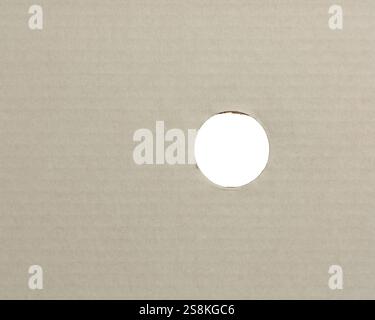 Weißer Oberflächenhintergrund aus Wellpappkarton mit rundem Loch oder Kreisschnitt, Belüftungsloch in der Verpackung Stockfoto