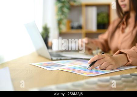 Nahaufnahme einer Innenarchitektin, die Farbmuster und Design-Layouts auf ihrem Schreibtisch überprüft Stockfoto