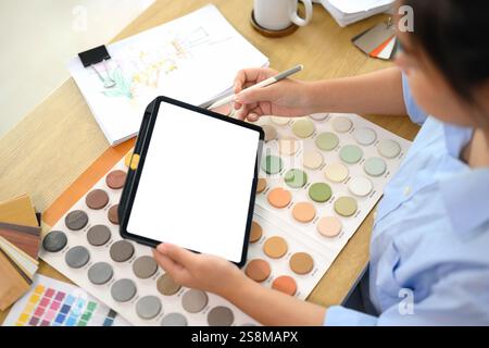 Kreative Frau, die ein digitales Tablet hält und Farbmuster für ein neues Innenarchitekturprojekt untersucht Stockfoto