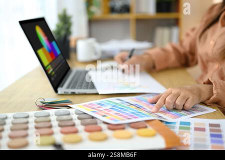 Nahaufnahme einer Innenarchitektin, die Farbmuster und Design-Layouts auf ihrem Schreibtisch überprüft Stockfoto