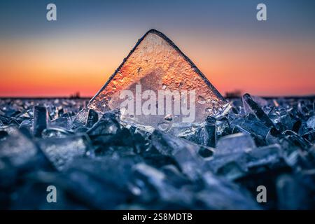 Fonyod, Ungarn – transparenter Eiswürfel auf dem gefrorenen Balaton an einem kalten Winternachmittag mit goldenen Sonnenuntergangslichtern Stockfoto