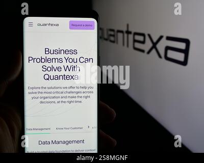 In dieser Abbildung hält eine Person ein Mobiltelefon mit der Webseite des britischen Datenanalyseunternehmens Quantexa Limited auf dem Bildschirm mit Logo. Stockfoto